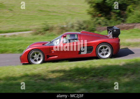 Ultima GTR rouge cramoisi dans profil (vue latérale) conduite rapide sur une route de campagne. Banque D'Images