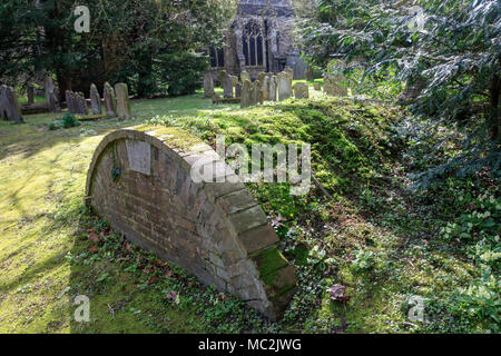 St Mildred's Churchyard au début du printemps, avec d'intéressants tombeaux voûtés en briques avec primroses dans l'herbe, Tenterden, Kent Banque D'Images