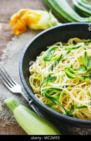 Les pâtes avec les courgettes sur fond de bois sombre dans un poêlon en fonte . La farine de grains entiers biologiques de spaghetti Banque D'Images