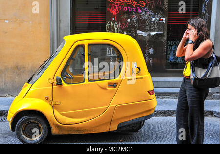Florence, Italie : Paysage, jeune femme debout près de la voiture jaune vif, parlant au téléphone Banque D'Images
