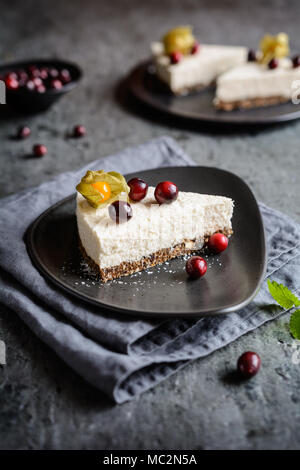 Pas de cuire le gâteau de noix de coco et yaourt aux fruits, les prunes séchées, les graines de chia et croûte garnie de canneberges fraîches et Physalis Banque D'Images