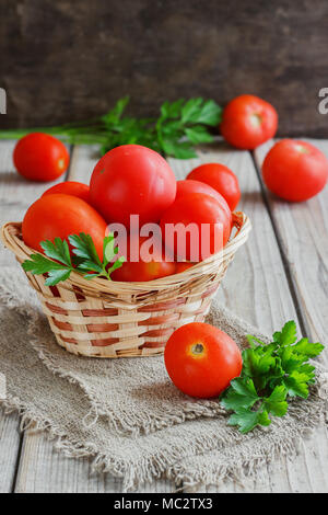 Les tomates rouges sur une planche en bois avec du persil. Mobilier de style Banque D'Images