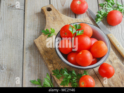 Les tomates rouges sur une planche en bois avec du persil. Mobilier de style Banque D'Images