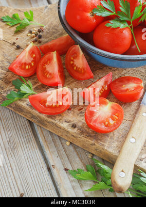 Les tomates rouges sur une planche en bois avec du persil. Mobilier de style Banque D'Images