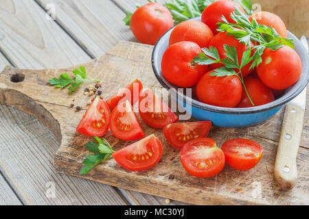 Les tomates rouges sur une planche en bois avec du persil. Mobilier de style Banque D'Images