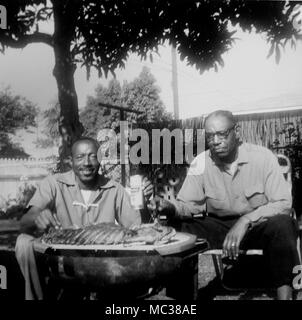 Deux hommes déguster une bière et les côtes dans l'arrière-cour en Californie, ca. 1960. Banque D'Images