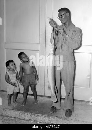 Un père de l'armée américaine montre l'Alligator Gar il a capturé dans le Sud américain à ses enfants, ca. 1961. Banque D'Images