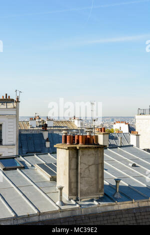 Vue dégagée sur les toits de Montmartre à Paris avec toiture en zinc, antennes de télévision, les lucarnes et les cheminées sous un ciel bleu clair. Banque D'Images