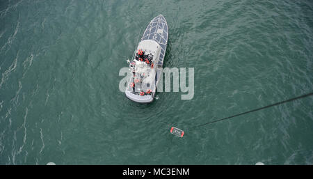 Un mécanicien de vol à bord d'un hélicoptère MH-65 de Dolphin Coast Guard Air Station Humboldt Bay abaisse une nacelle de sauvetage d'une embarcation à moteur de 47 pieds au cours de la formation de l'équipage, à Eureka, Californie, le 7 mars 2018. Les équipages des hélicoptères de la Garde côtière canadienne effectuent couramment des équipages de petits bateaux avec formation de maintenir leurs qualifications et ainsi que dans le cas d'une évacuation sanitaire demande d'un bateau ou navire, les équipages sont compétents dans leurs techniques de sauvetage. Banque D'Images