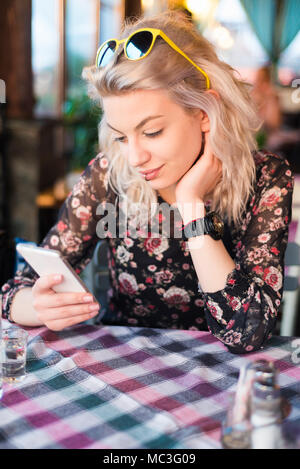 Belle jeune femme à la recherche lors de l'attente au téléphone Banque D'Images