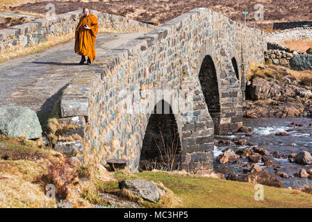 Moine en tenir l'appareil photo marchait sur vieux pont Sligachan, Isle of Skye, Scotland, UK en Mars Banque D'Images