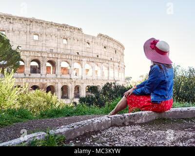 Vue de côté élégant anonyme femme assise seule et rêve sur fond de belle du Colisée de Rome. Banque D'Images