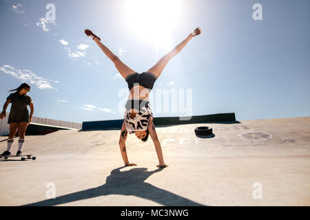 Les filles actions stunts au skate park. Les femmes qui font un flip avec ami équitation sur un long bord. Banque D'Images