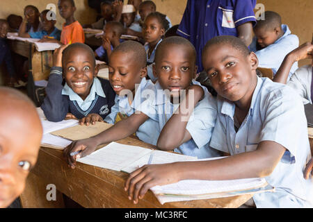 L'Ouganda. 13 juin 2017. Les enfants ougandais souriant assis à un bureau dans une salle de classe de l'école primaire de Kayanja. Banque D'Images