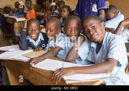 L'Ouganda. 13 juin 2017. Les enfants ougandais souriant assis à un bureau dans une salle de classe dans une école primaire. Banque D'Images