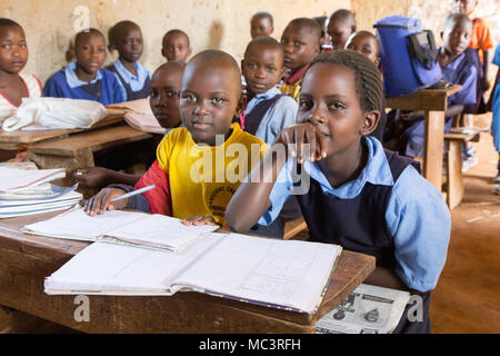 L'Ouganda. 13 juin 2017. Les enfants ougandais souriant assis à un bureau dans une salle de classe dans une école primaire. Banque D'Images