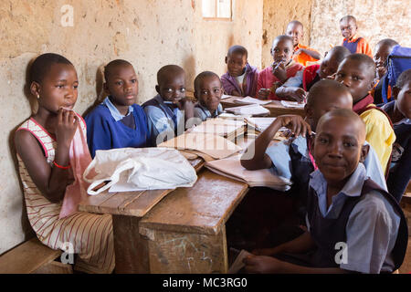 L'Ouganda. 13 juin 2017. Les enfants ougandais souriant assis à un bureau dans une salle de classe dans une école primaire. Banque D'Images