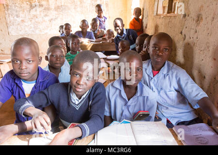 L'Ouganda. 13 juin 2017. Les enfants ougandais souriant assis à un bureau dans une salle de classe dans une école primaire. Banque D'Images