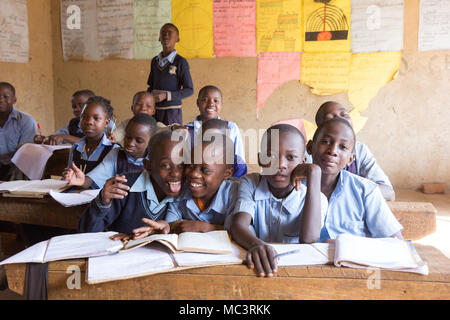 L'Ouganda. 13 juin 2017. Les enfants ougandais souriant assis à un bureau dans une salle de classe dans une école primaire. Banque D'Images