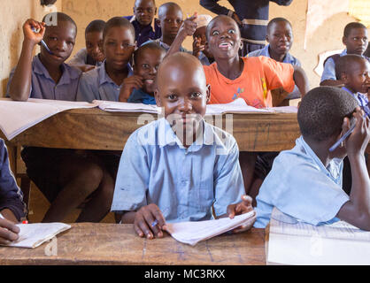 L'Ouganda. 13 juin 2017. Les enfants ougandais souriant assis à un bureau dans une salle de classe dans une école primaire. Banque D'Images