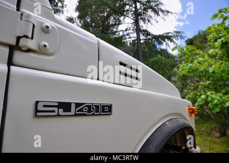 Détail de carrosserie y compris le numéro de modèle la plaque d'un blanc Suzuki SJ410 véhicule hors-route avec des arbres et du ciel en arrière-plan. Banque D'Images