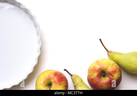 Céramique blanche vide tart ou circulaire allant au four, sur le tableau blanc, avec des pommes et des poires ; with copy space Banque D'Images