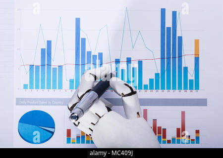 Close-up d'une main robotique en utilisant un stylo tout en travaillant sur le graphique Banque D'Images