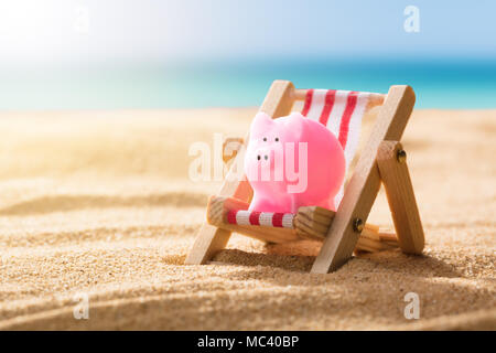 Close-up of Pink Piggy Bank sur une chaise longue à la plage Banque D'Images