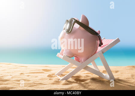 Close-up of a Pink Piggy Bank Wearing Sunglasses Relaxing On Deck Chair Banque D'Images