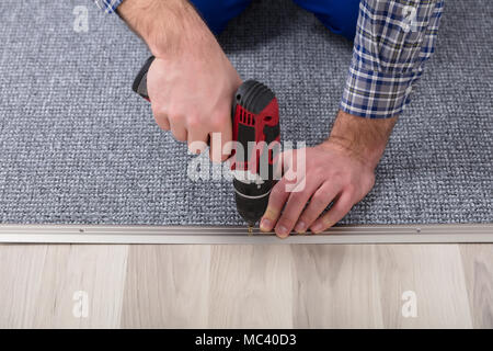 Close-up d'un ajusteur de Tapis Tapis gris la main de l'installation avec tournevis sans fil Banque D'Images