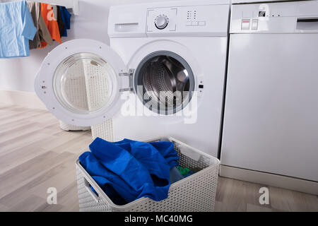 Lave-linge vide avec des tas de vêtements sales dans le panier à la Buanderie Banque D'Images