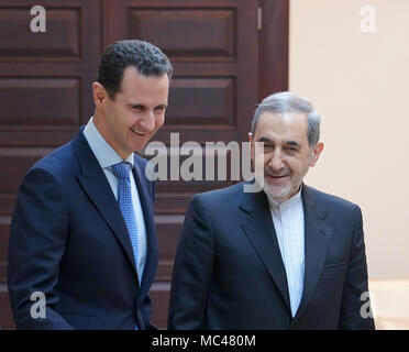 Damas, Syrie. Apr 12, 2018. Le président syrien Bachar al-Assad (L) parle d'Ali Akbar Velayati, conseiller principal de l'Iran l'Ayatollah Ali Khamenei, à Damas, capitale de la Syrie, le 12 avril 2018. Le président syrien Bachar al-Assad a déclaré jeudi que les États-Unis menace de grève la Syrie de déstabiliser davantage la région, l'agence SANA a rapporté. Credit : présidence syrienne/Xinhua/Alamy Live News Banque D'Images