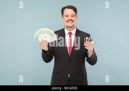 Businessman détient beaucoup d'euros et beaucoup de cartes bancaires. Piscine, studio shot, isolé sur fond gris ou bleu clair Banque D'Images