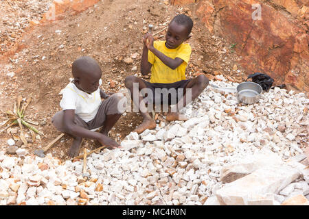 Lugazi, en Ouganda. 18 juin 2017. Garçons ougandais casser des pierres dans les petites dalles pour les vendre à leur contremaître. Fondamentalement, le travail des enfants. Banque D'Images