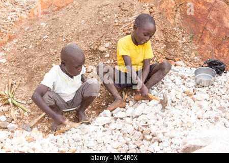 Lugazi, en Ouganda. 18 juin 2017. Garçons ougandais casser des pierres dans les petites dalles pour les vendre à leur contremaître. Fondamentalement, le travail des enfants. Banque D'Images