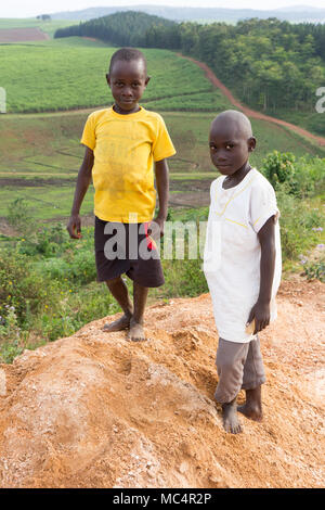 Lugazi, en Ouganda. 18 juin 2017. Smiling garçons ougandais debout sur le sommet d'une montagne au-dessus les régions rurales de l'Ouganda. Banque D'Images