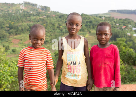 Lugazi, en Ouganda. 18 juin 2017. Smiling garçons ougandais debout sur le sommet d'une montagne au-dessus les régions rurales de l'Ouganda. Banque D'Images