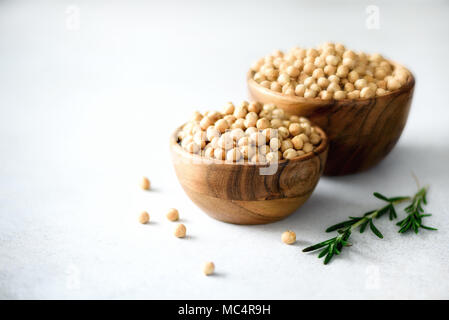 Pois chiches en matières premières biologiques bols en bois et de romarin sur fond de béton gris. Les ingrédients des aliments sains. Copier l'espace. Banner Banque D'Images