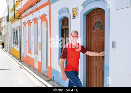 Jeune homme avec maillot de l'équipe nationale de football portugais entrant dans une maison typique à Tavira Banque D'Images