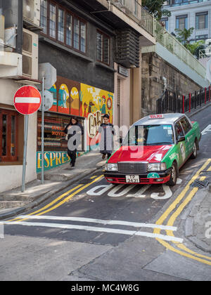 Hong Kong taxi Cab négocie une rue raide dans le quartier des niveaux moyens de la ville. Banque D'Images