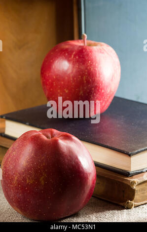 Deux pommes rouges sur un ancien vintage books éclairée par une lumière vive à partir de la fenêtre avec une faible profondeur de champ Banque D'Images