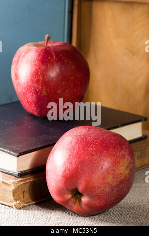 Deux pommes rouges sur un ancien vintage books éclairée par une lumière vive à partir de la fenêtre avec une faible profondeur de champ Banque D'Images