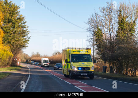 Une ambulance avec feux bleus clignotants sur une route principale dans la région de Suffolk , Angleterre , Royaume-Uni Banque D'Images