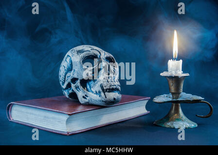 Crâne gothique sur old book and candle en chandelier sur fond sombre et fumé. Halloween concept. Banque D'Images
