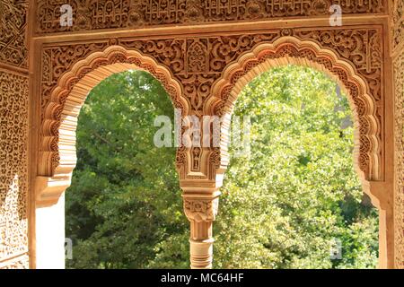 Les détails de la sculpture sur pierre complexes entourant les fenêtres en forme de fer à cheval du Palais de l'Alhambra, Grenade, Espagne Banque D'Images