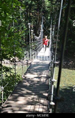 Des randonnées à travers une femme pont suspendu de l'Olympic National Park, Washington USA Banque D'Images