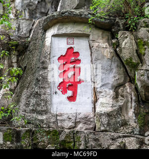 Une inscription et la sculpture sur pierre à la base du pic de la beauté solitaire, Guilin, Chine. Le caractère chinois peint rouge est Shou, qui signifie la longévité. Banque D'Images