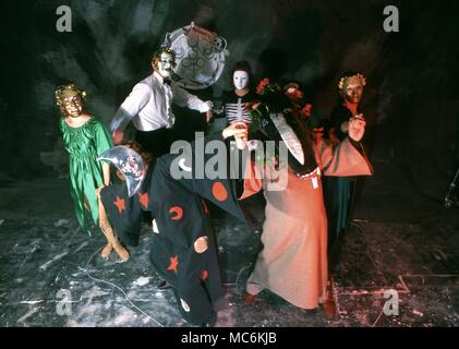 Un groupe de personnes dans une sorcellerie burlesque, vêtus de costumes bizarres et des masques, la danse à l'intérieur d'un cercle magique. Banque D'Images