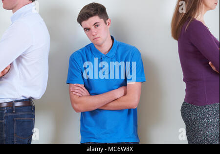 Portrait of Teenage Boy Standing entre les parents qui ne respectent pas les uns les autres Banque D'Images