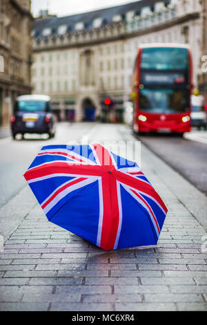 Londres, Angleterre - parapluie britannique à Regent Street avec rouge iconique double-decker bus et taxi noir en mouvement Banque D'Images